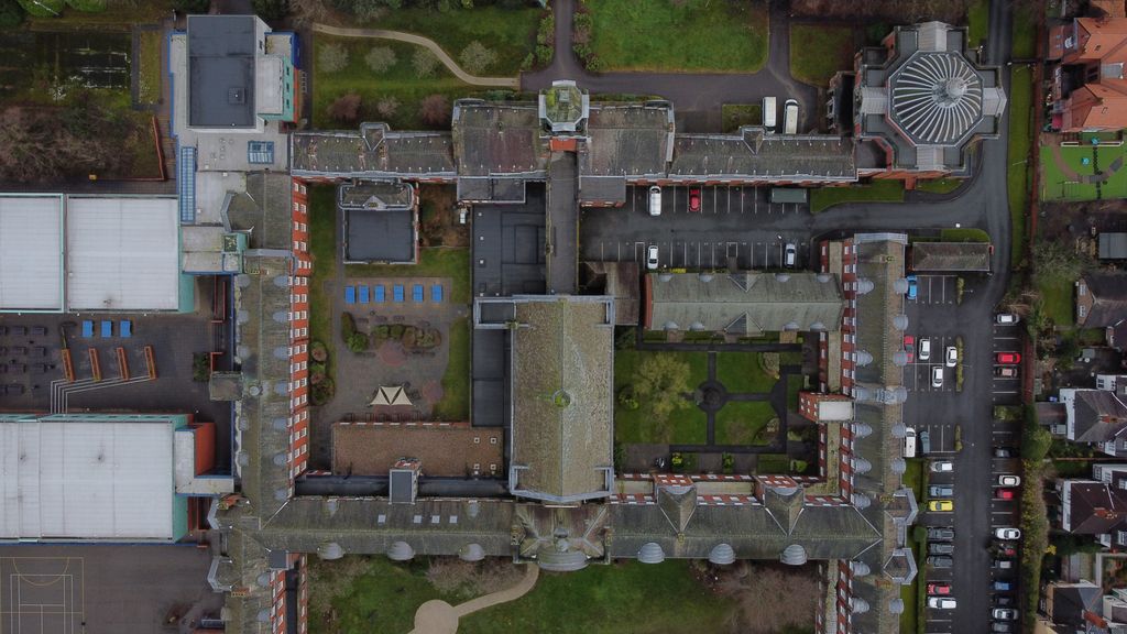 Aerial view of a historic building complex and parking lot in an English city.