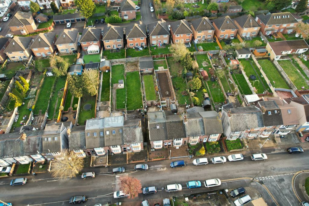 High-angle aerial shot of a residential neighborhood in Luton, UK, showcasing houses and gardens.